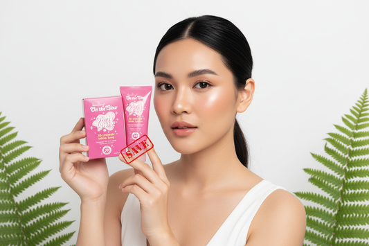 Woman with radiant glowing skin holding i-Fern brightening soap and lotion, soft natural lighting with green fern leaves